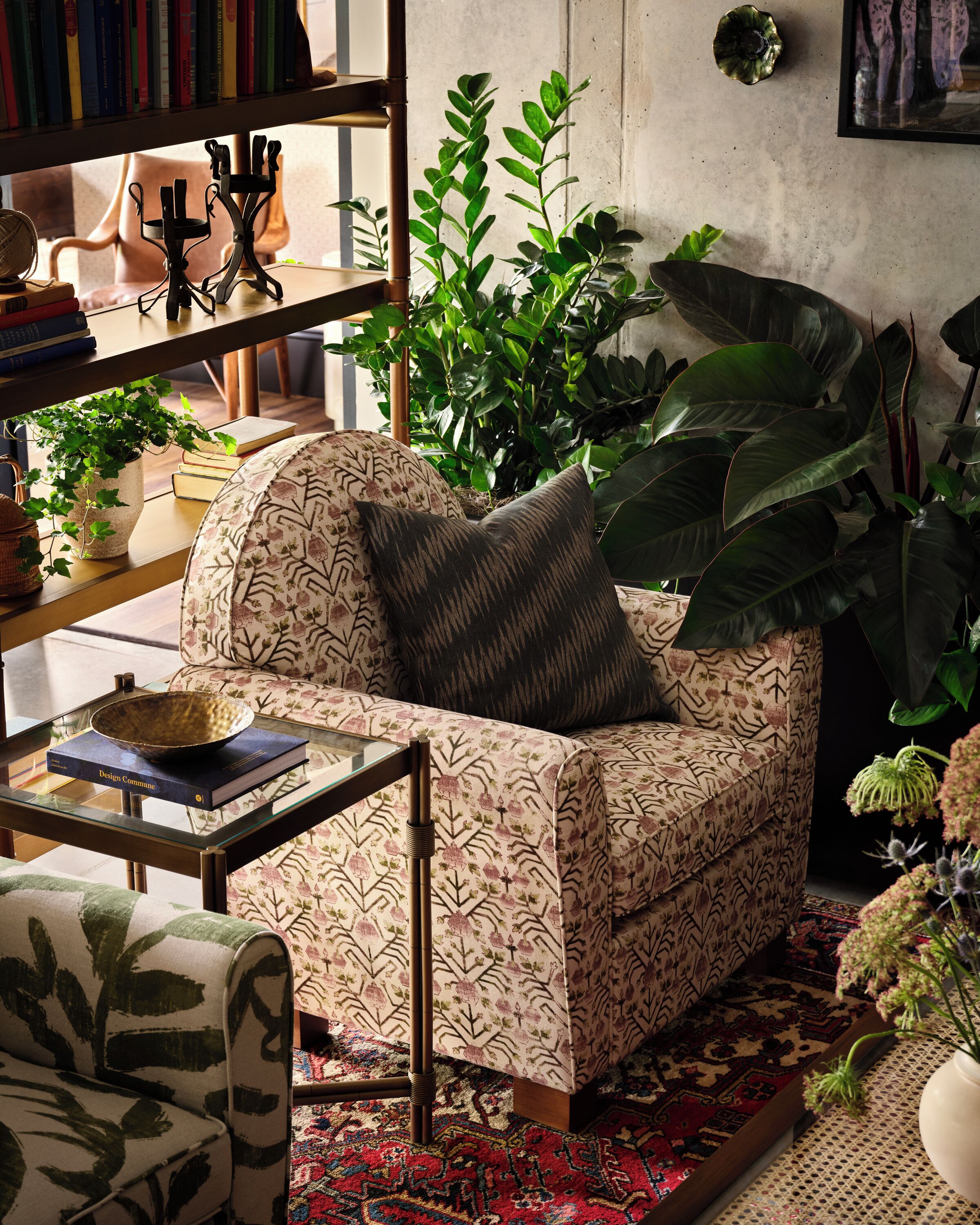 A cozy living room with a patterned sofa, a glass coffee table, and a bookshelf filled with books.