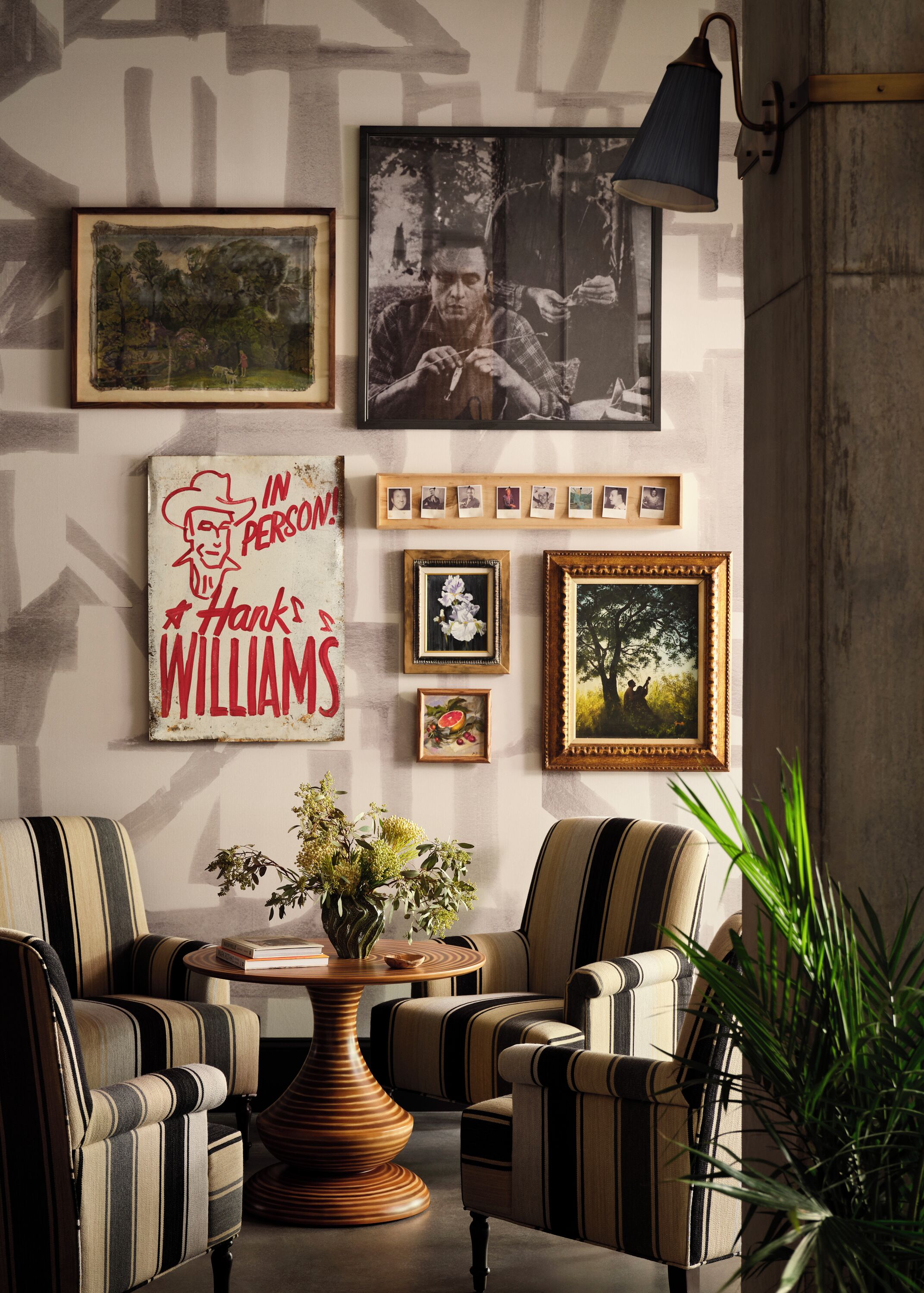 A cozy living room with striped armchairs, a coffee table with a vase, and a wall adorned with framed pictures and a sign.