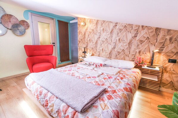A bedroom with a bed, a red chair, a nightstand, and a wall with a leaf pattern. - Flytosuite aeroporto attico mansarda (Calderara di Reno)