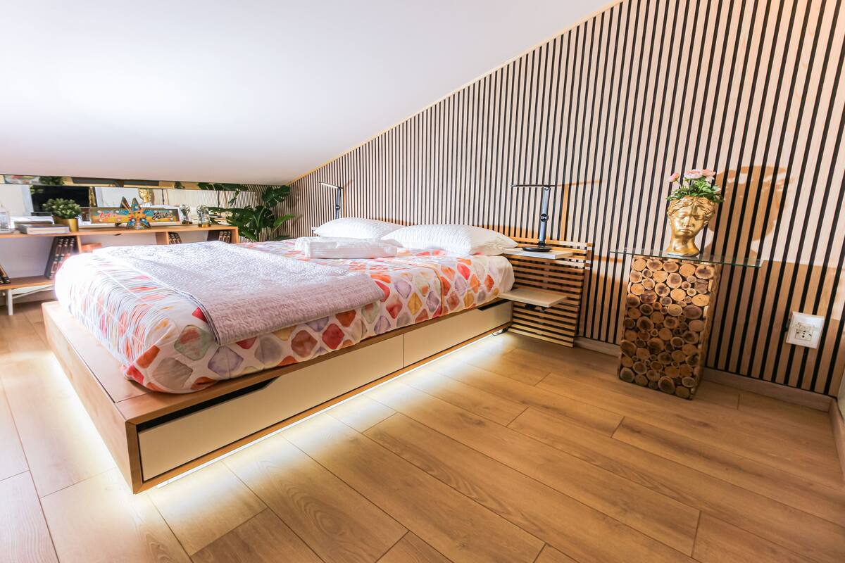 A modern bedroom with a bed, bedside tables, and a decorative sculpture.