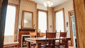 Une salle à manger avec une table et des chaises en bois, un lustre et un papier peint à motifs.