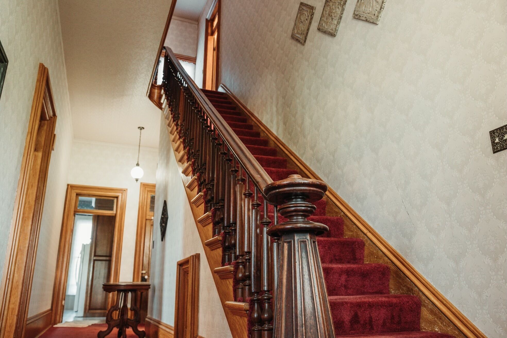 Eine prächtige Treppe mit hölzernen Geländern und einem mit rotem Teppich belegten Podest.