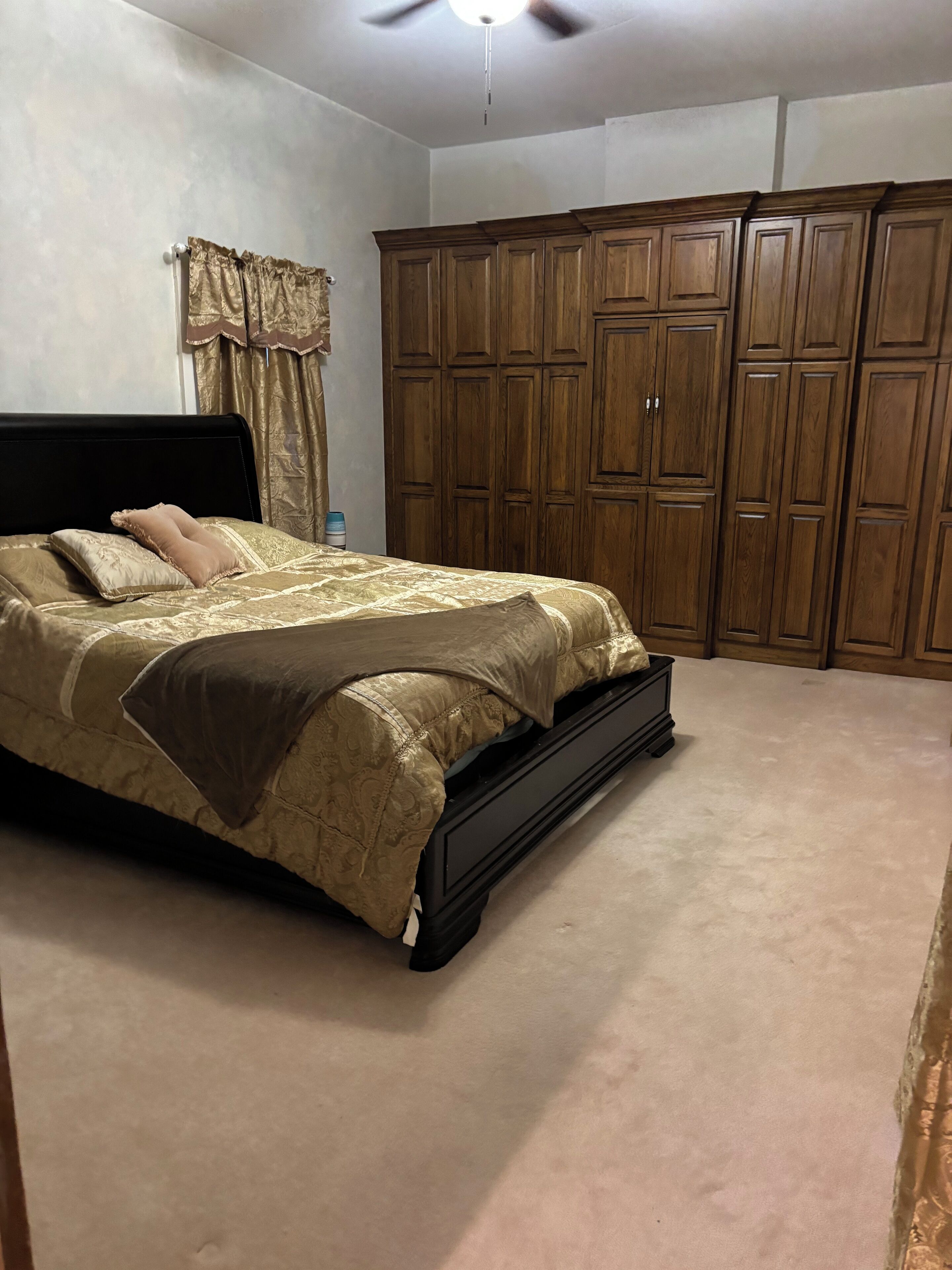 A bedroom with a bed, a wardrobe, and a ceiling fan.