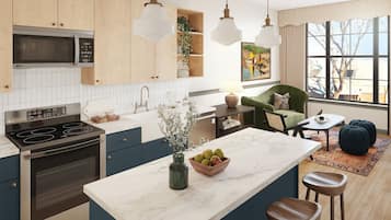 A modern kitchen with wooden cabinets, a built-in microwave, an oven, and a marble island with stools.