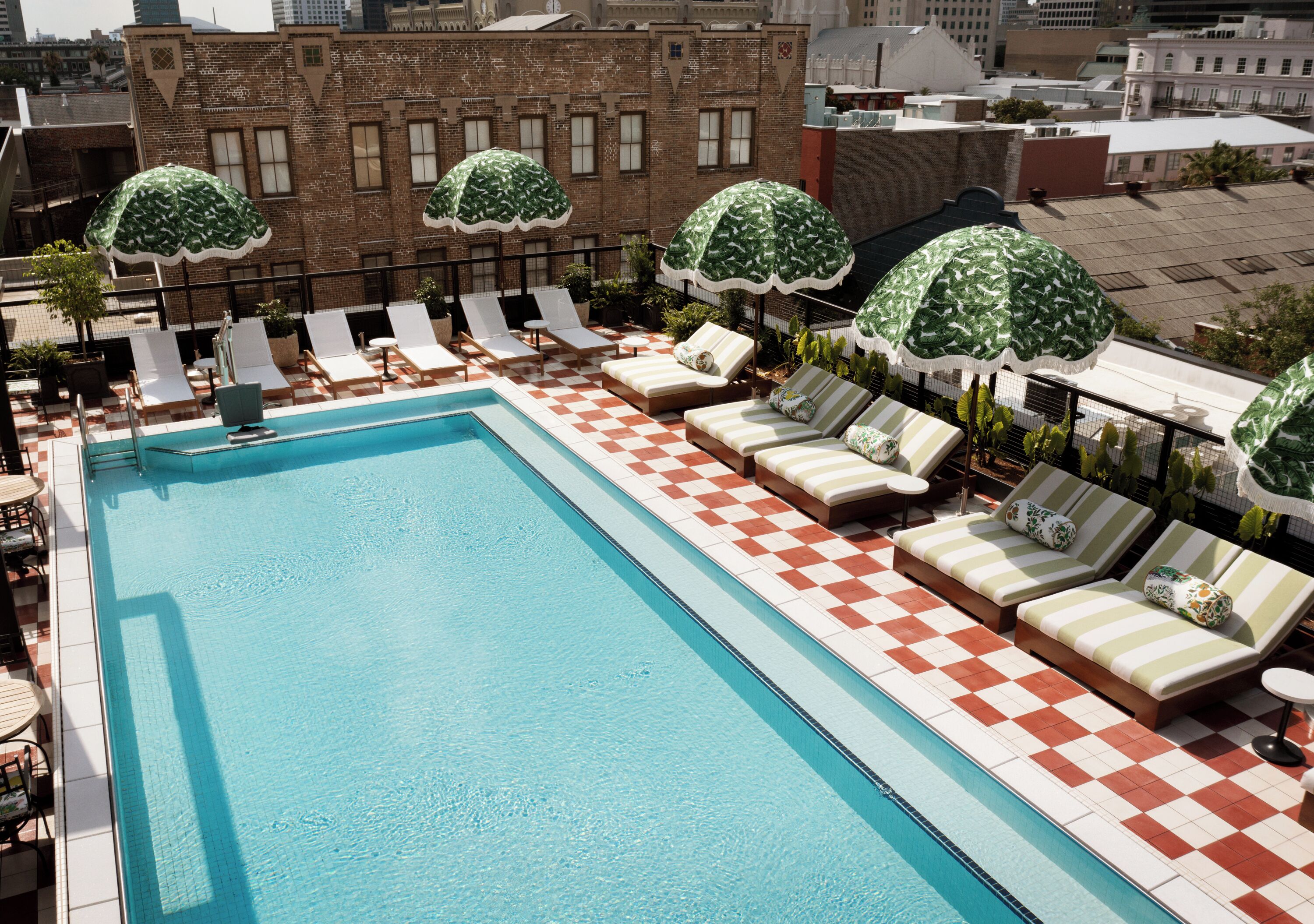 Un espace piscine aménagé sur le toit, avec un sol à carreaux, des chaises longues et des parasols.