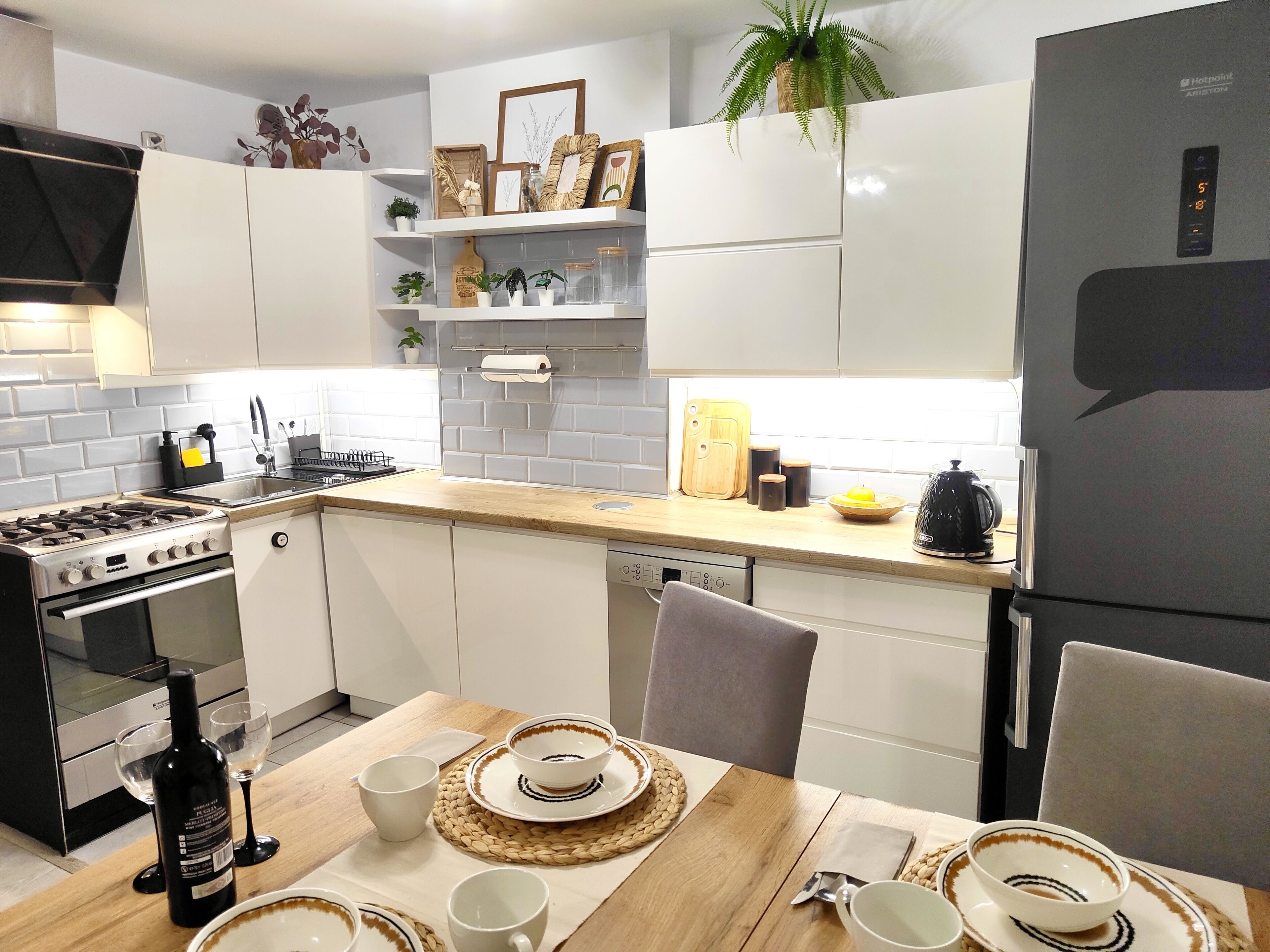 A modern kitchen with white cabinets, a stove, a dishwasher, and a refrigerator.