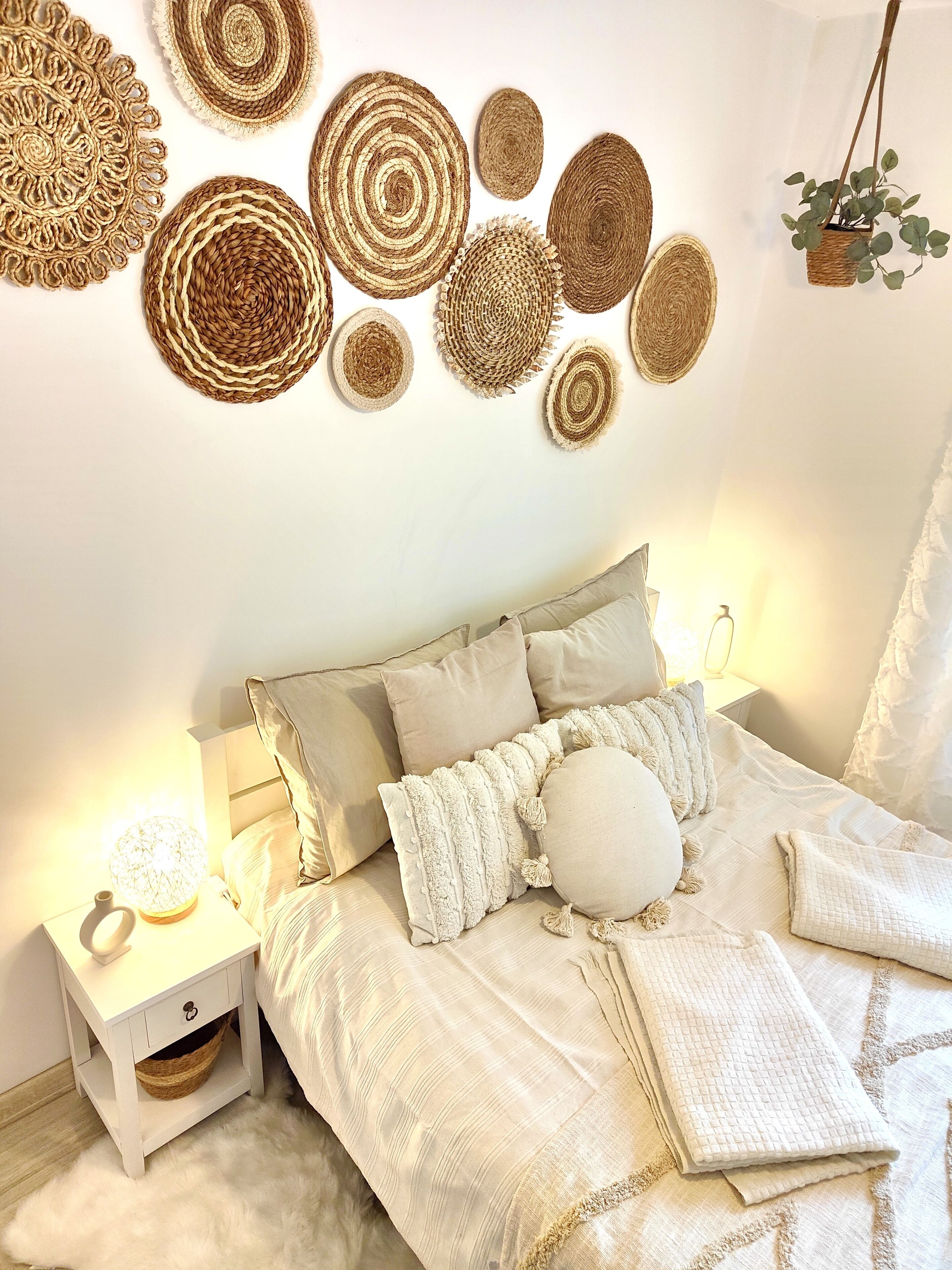 Une chambre à coucher comprenant un lit, des oreillers, une table de chevet, une lampe et un mur décoré de tentures murales tissées.