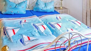 A bed with a blue and white sailboat pattern, a matching pillow, and a striped blanket. - Ferienwohnung Friedrichroda (Friedrichroda)