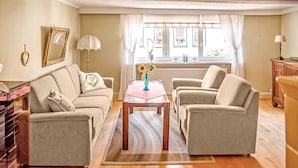 A living room with a beige sofa set, a coffee table, and a window with curtains. - Ferienwohnung Friedrichroda (Friedrichroda)
