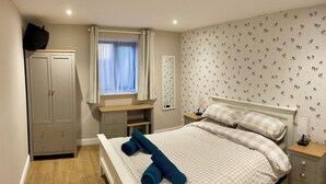 A bedroom with a bed, a wardrobe, a desk, and a window with curtains. - Blackberry Cottage - Cosy Autumn Getaway in Cardiff

 (Cardiff)