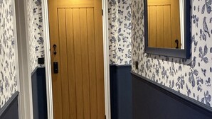 A hallway with patterned wallpaper, a wooden door, and a mirror on the wall. - Blackberry Cottage - Cosy Autumn Getaway in Cardiff

 (Cardiff)