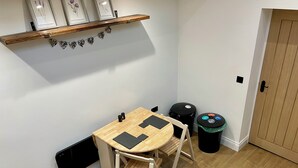 A corner room with a wooden table, two chairs, a black trash bin, and a door. - Blackberry Cottage - Cosy Autumn Getaway in Cardiff

 (Cardiff)