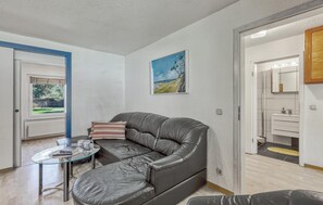 Una sala moderna con un sofá de cuero, una mesa de centro de vidrio y un cuadro en la pared.