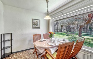 Un comedor con una mesa dispuesta para cuatro personas, un jarrón con flores y un cuadro en la pared.
