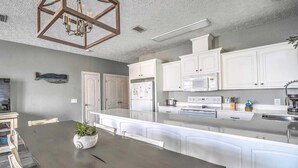 A modern kitchen with white cabinets, a central island, and a dining table with chairs.