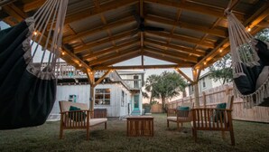 An outdoor seating area with wooden furniture and hammocks under a wooden roof structure. - Lower · 2/1 - Lower Unit - 4 Blocks to the Beach (Jacksonville Beach)