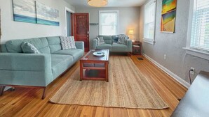 A living room with two sofas, a coffee table, a rug, and a hanging light fixture. - Lower · 2/1 - Lower Unit - 4 Blocks to the Beach (Jacksonville Beach)