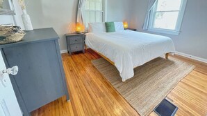 A bedroom with a bed, bedside tables, a dresser, a ceiling fan, and a window. - Lower · 2/1 - Lower Unit - 4 Blocks to the Beach (Jacksonville Beach)