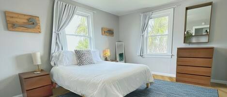 A bedroom with a bed, nightstand, dresser, and a ceiling fan.