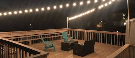 A wooden deck with a railing, a table, and two chairs.
