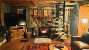 A cozy living room with a fireplace, wooden furniture, and a television.