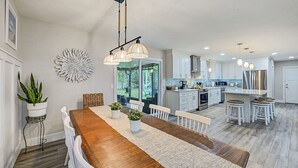 Une cuisine moderne avec des armoires blanches, des appareils en acier inoxydable et des luminaires suspendus.