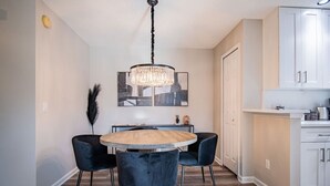 A dining area with a round table, four chairs, a chandelier, and a cityscape artwork on the wall. - NEW! Coastal Haven: beach, bikes, near Mayo, golf (Ponte Vedra Beach)