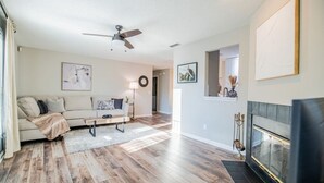 A living room with a sofa, coffee table, fireplace, and artwork on the walls. - NEW! Coastal Haven: beach, bikes, near Mayo, golf (Ponte Vedra Beach)