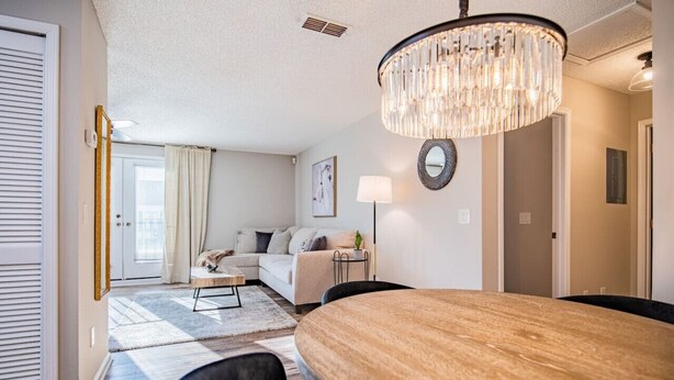 A modern living room with a wooden dining table, a chandelier, and a sofa. - NEW! Coastal Haven: beach, bikes, near Mayo, golf (Ponte Vedra Beach)