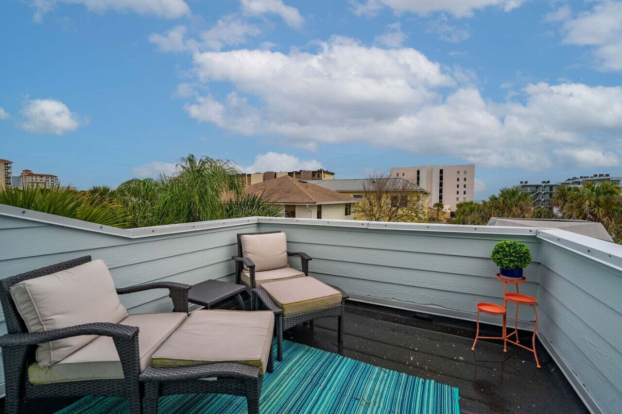 Une terrasse sur le toit, aménagée avec des meubles en osier, une petite table et une plante en pot.