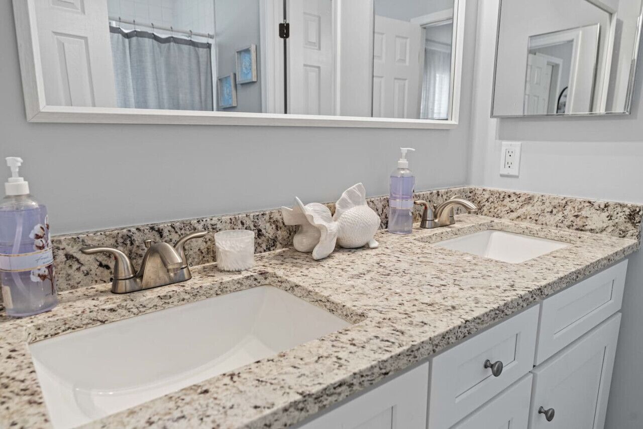 A bathroom with two sinks, a large mirror, and a granite countertop.