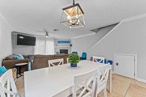 Una sala moderna con una mesa de comedor blanca, un sofá y un ventilador de techo.