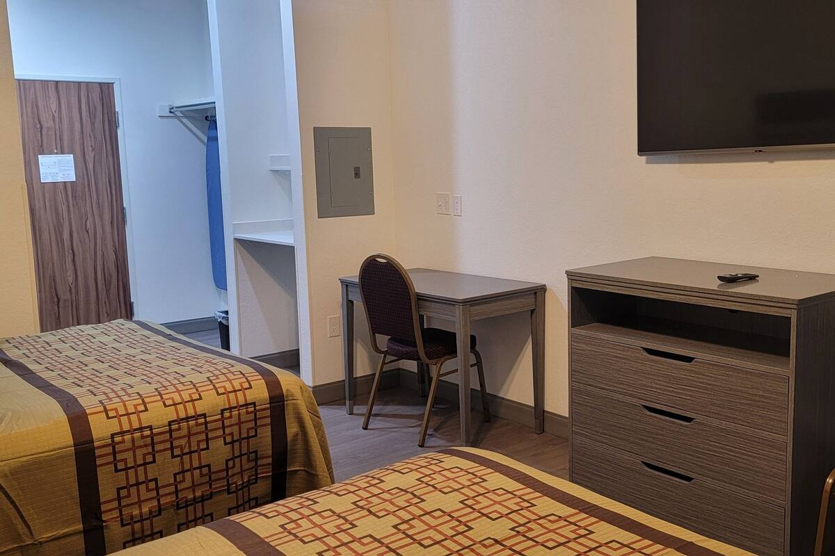 Un dormitorio con dos camas, un escritorio, una silla y un televisor.