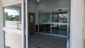 A hotel entrance with a sliding glass door, a welcome sign, and a view of the parking lot. - Texas Bungalows Hotel & Hotel Que at i35 Austin Pflugerville (Pflugerville)