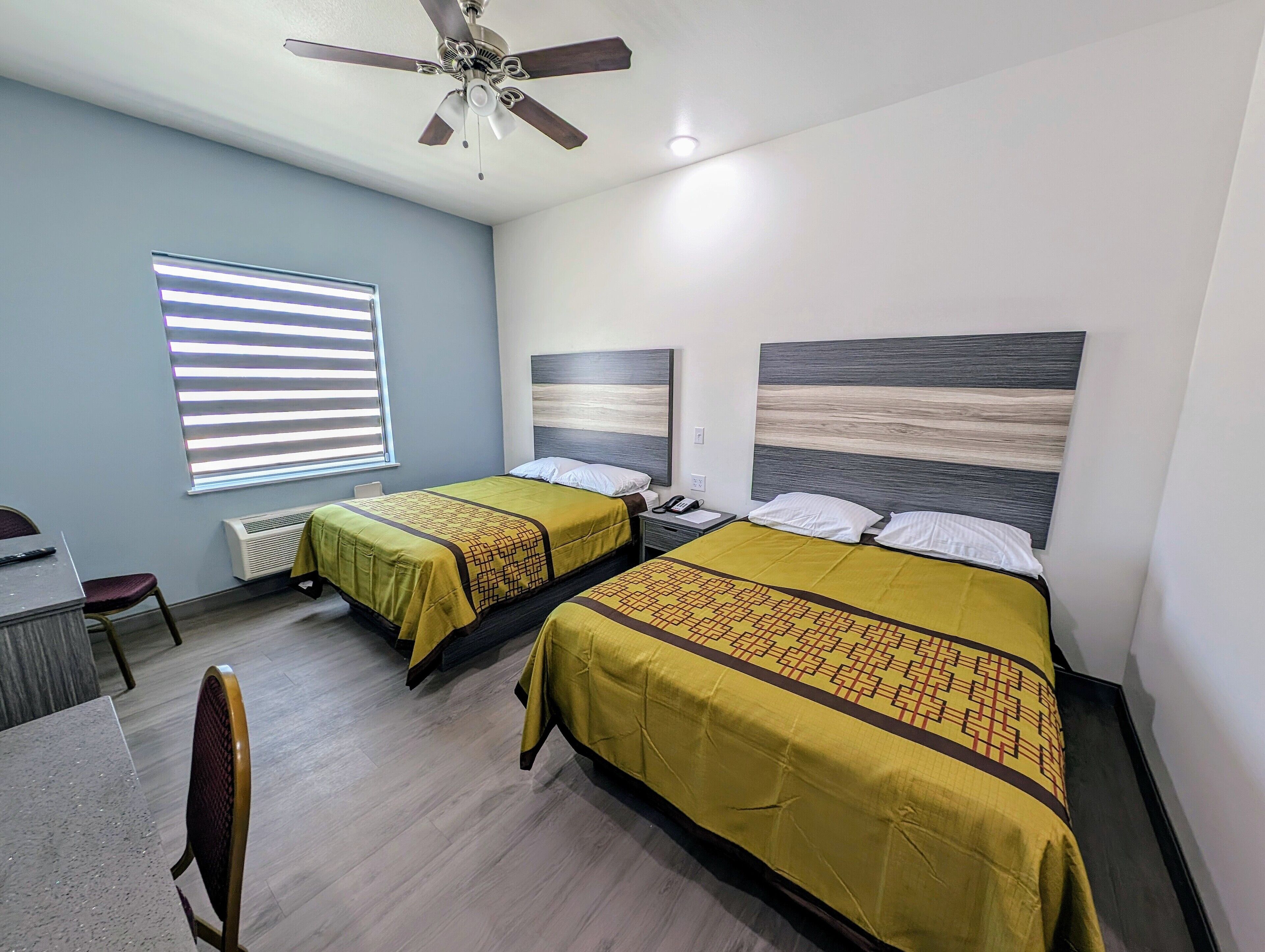 Quarto de hotel com duas camas, uma escrivaninha e uma cadeira.