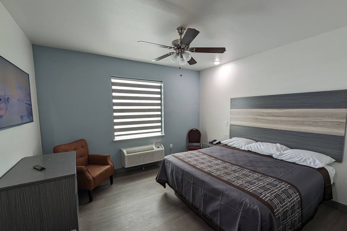 Un dormitorio con cama, escritorio, silla, radiador y ventilador de techo.