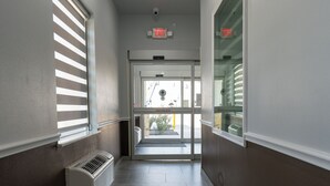 A hallway with a radiator, a glass door leading outside, and a ceiling light. - Texas Bungalows Hotel & Hotel Que at i35 Austin Pflugerville (Pflugerville)