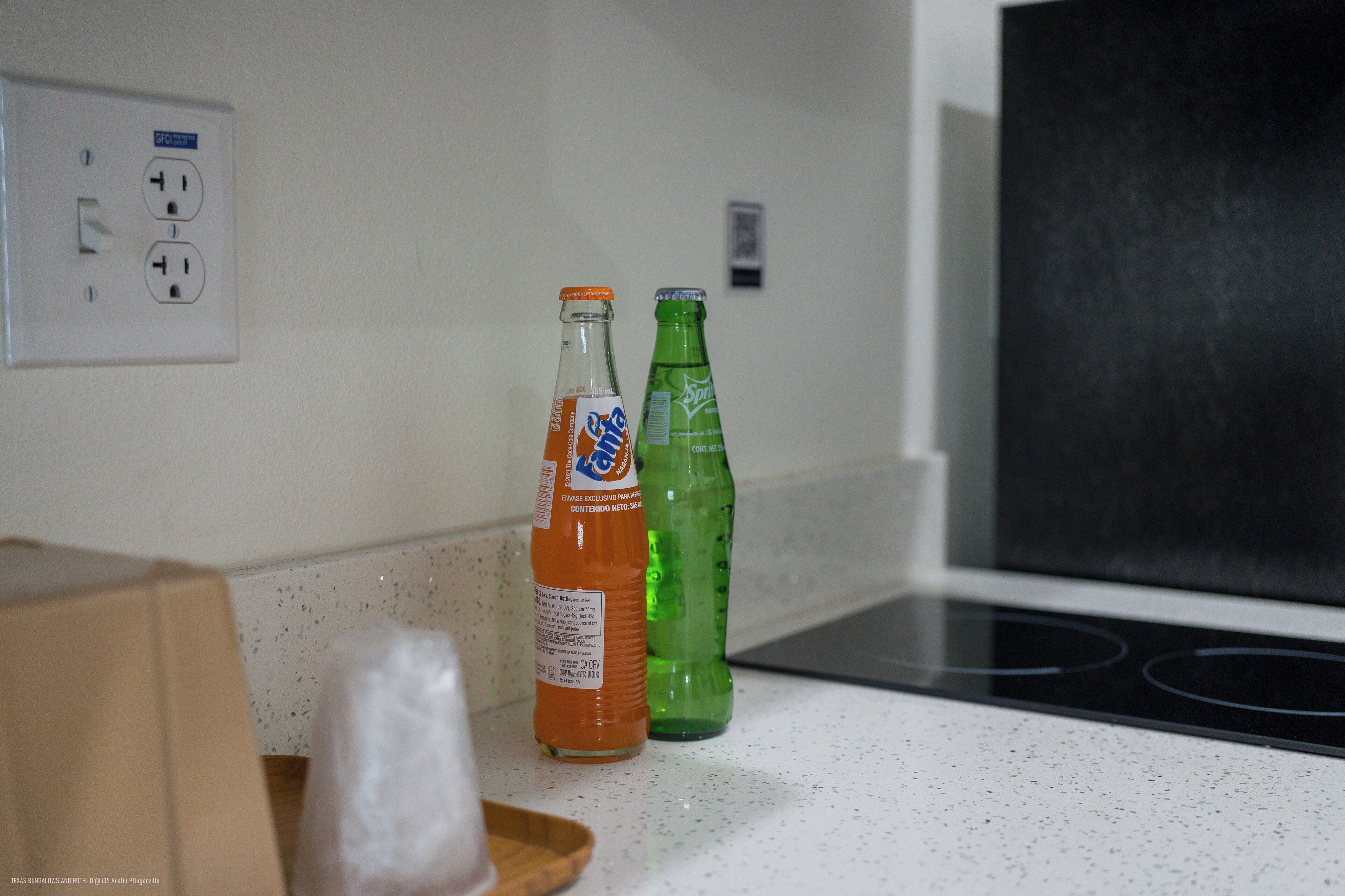 A kitchen with a white countertop, a black stove, and two bottles of soda.