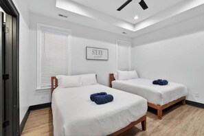 A hotel room with two beds, a ceiling fan, and a 'STAY' sign on the wall. - Two Homes, One Booking | Sleeps 20 | 6BR/4BA Chattanooga Compound | Hot Tub · Pool Table (Chattanooga)