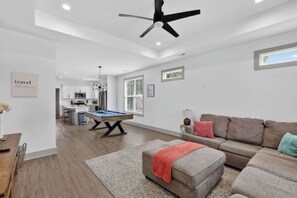 A modern living room with a pool table, a sofa, and a ceiling fan. - Two Homes, One Booking | Sleeps 20 | 6BR/4BA Chattanooga Compound | Hot Tub · Pool Table (Chattanooga)