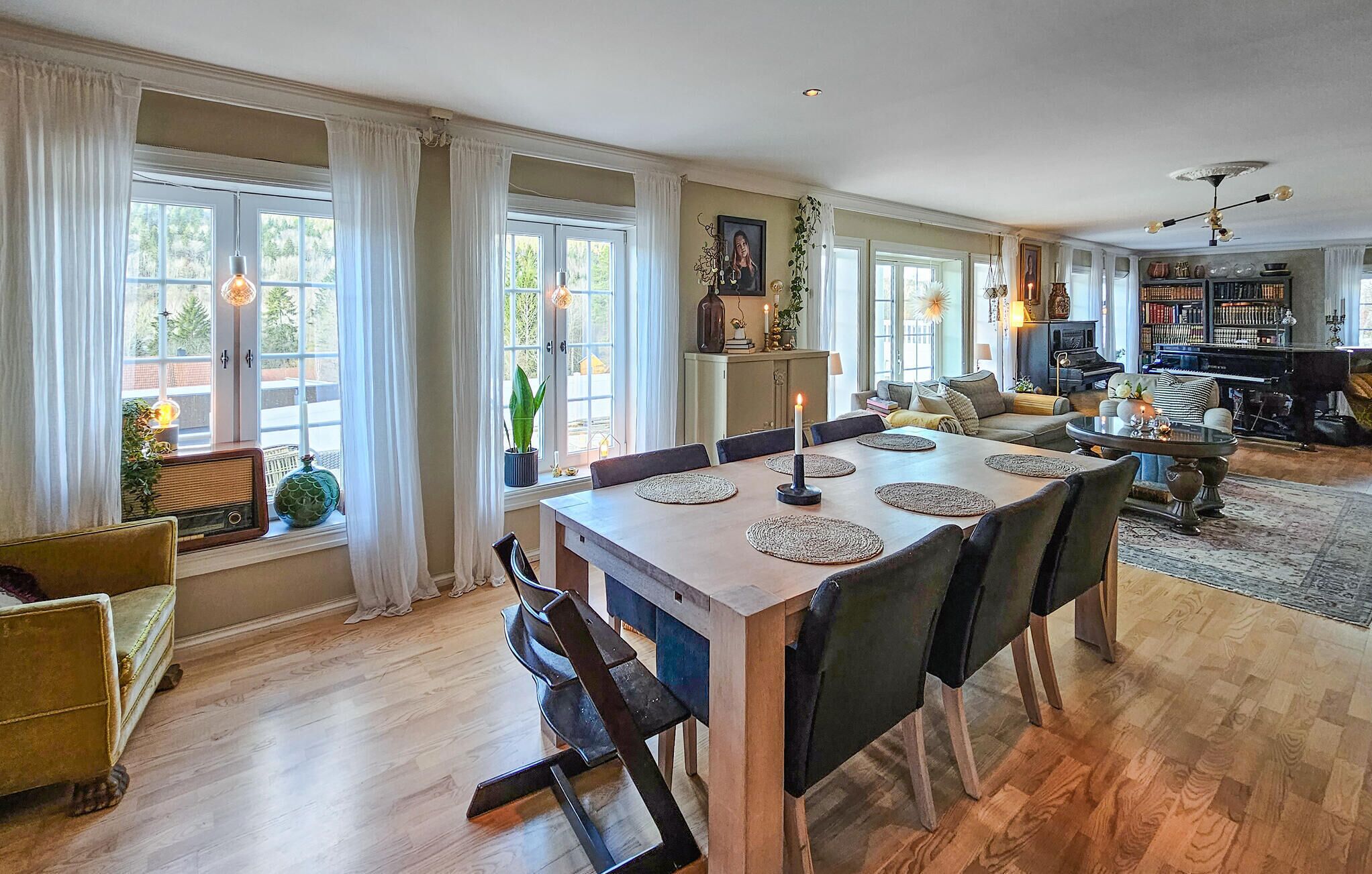 A spacious living room with a dining area, large windows, and a fireplace.