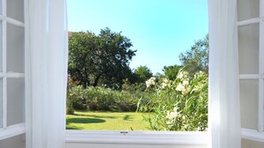 Una stanza con un tavolo apparecchiato per due, una finestra con tende e vista su un giardino.