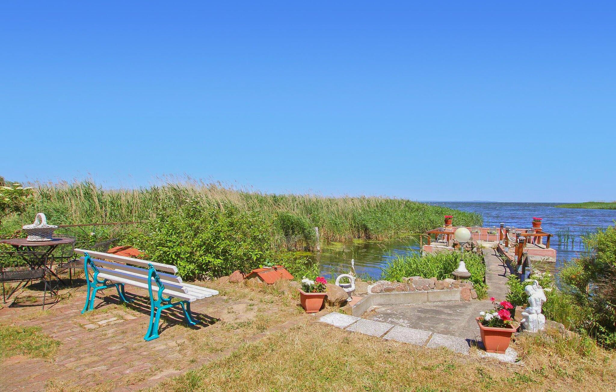 Un parc au bord de la rivière, avec un banc, des plantes en pot et une statue.