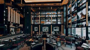 Un restaurant doté d’un espace central où sont disposées les tables, entouré d’étagères remplies de divers objets.