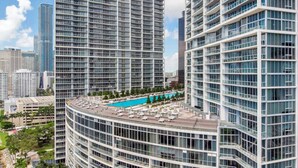 Un immeuble de grande hauteur doté d’une piscine sur le toit, entouré d’autres bâtiments imposants.