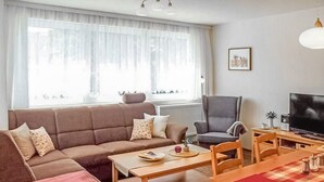 A living room with a sofa, armchair, coffee table, and a TV. - Ferienwohnung Dierhagen (Dierhagen (Ostseebad))