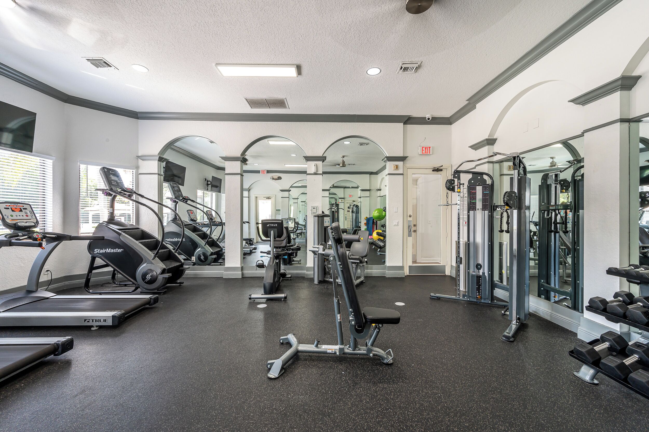 A gym with treadmills, weight machines, and dumbbells.