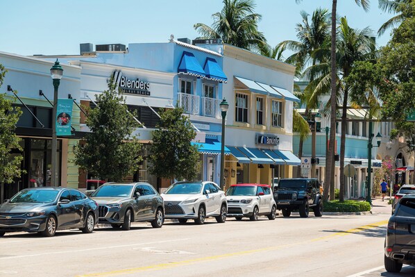 Vista de la calle con coches estacionados, un edificio con el letrero "Blenders Delray Beach" y palmeras.