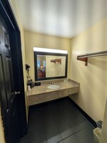 Un baño con lavamanos, espejo y perchero para toallas.