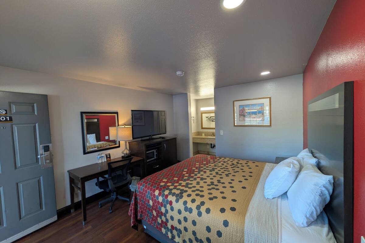 A hotel room with a bed, desk, television, and a door marked "01".